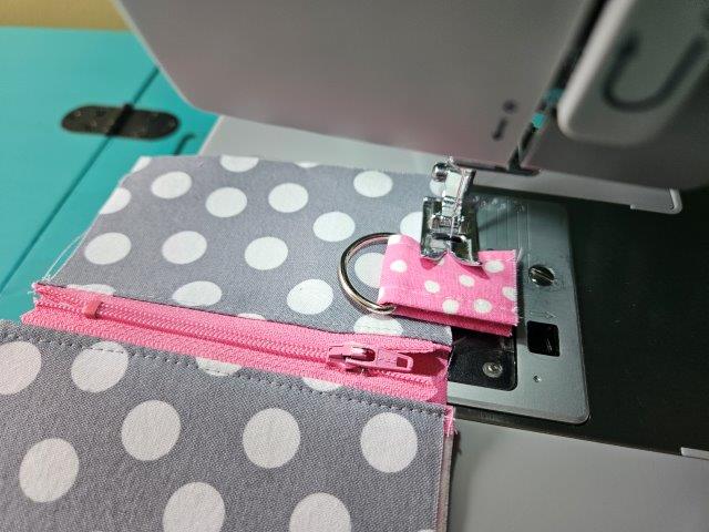 Baste the short strap to the front of the mini zipper pouch