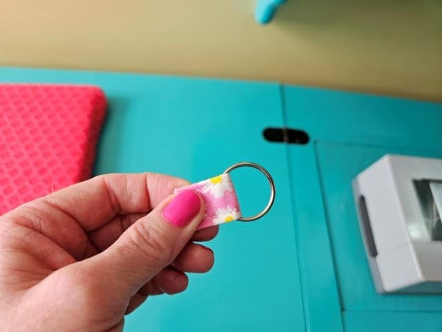 Slip the lip balm holder strap through the split ring and fold in half