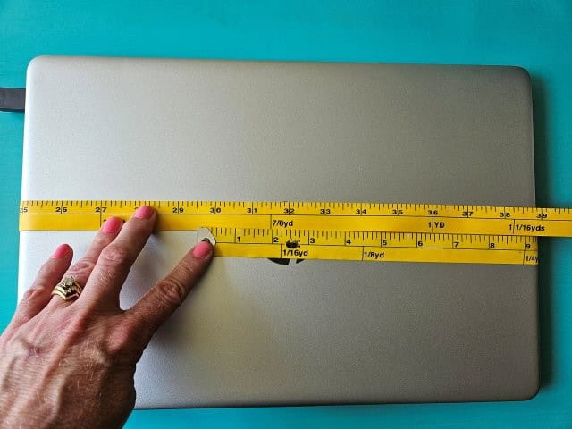 Wrap measuring tap around the width of the laptop
