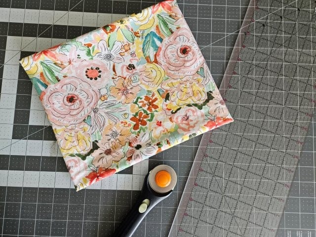 Fabric, rotary cutter, clear ruler, and cutting mat for pillowcase tutorial
