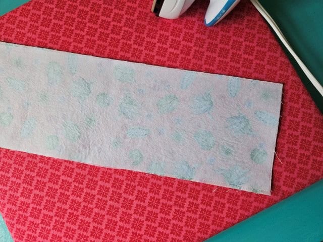 Place the tote bag strap wrong side up on ironing board